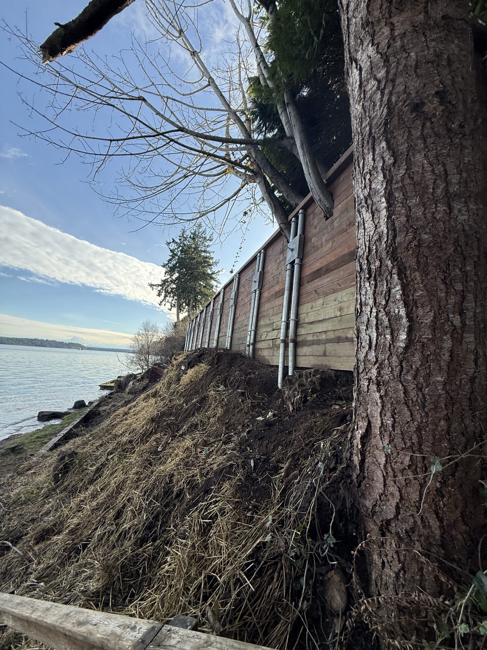 a large wooden retaining wall on a hill by water